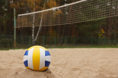 Colorful volleyball ball on sand court, space for text