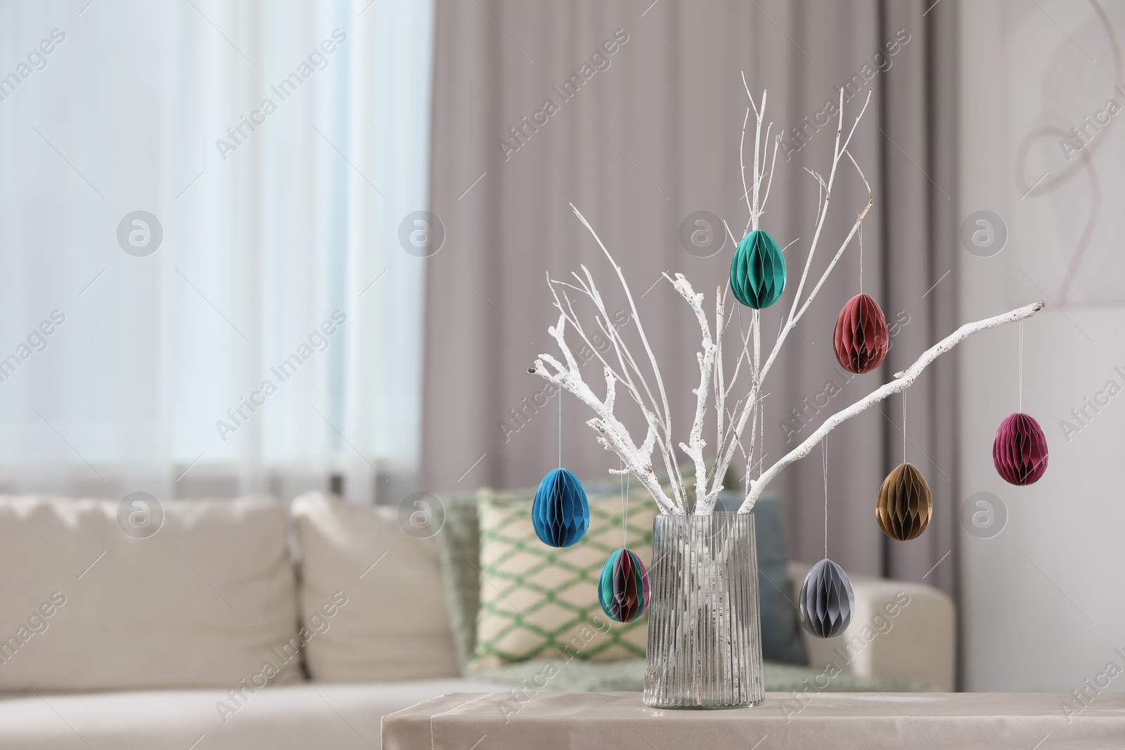 Photo of Branches with paper eggs in vase on table at home, space for text. Beautiful Easter decor.