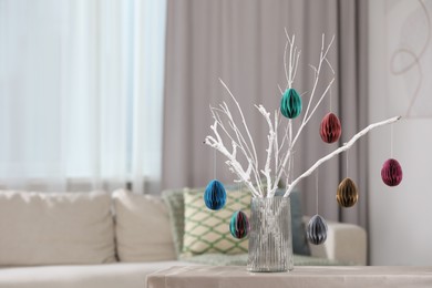 Branches with paper eggs in vase on table at home, space for text. Beautiful Easter decor.