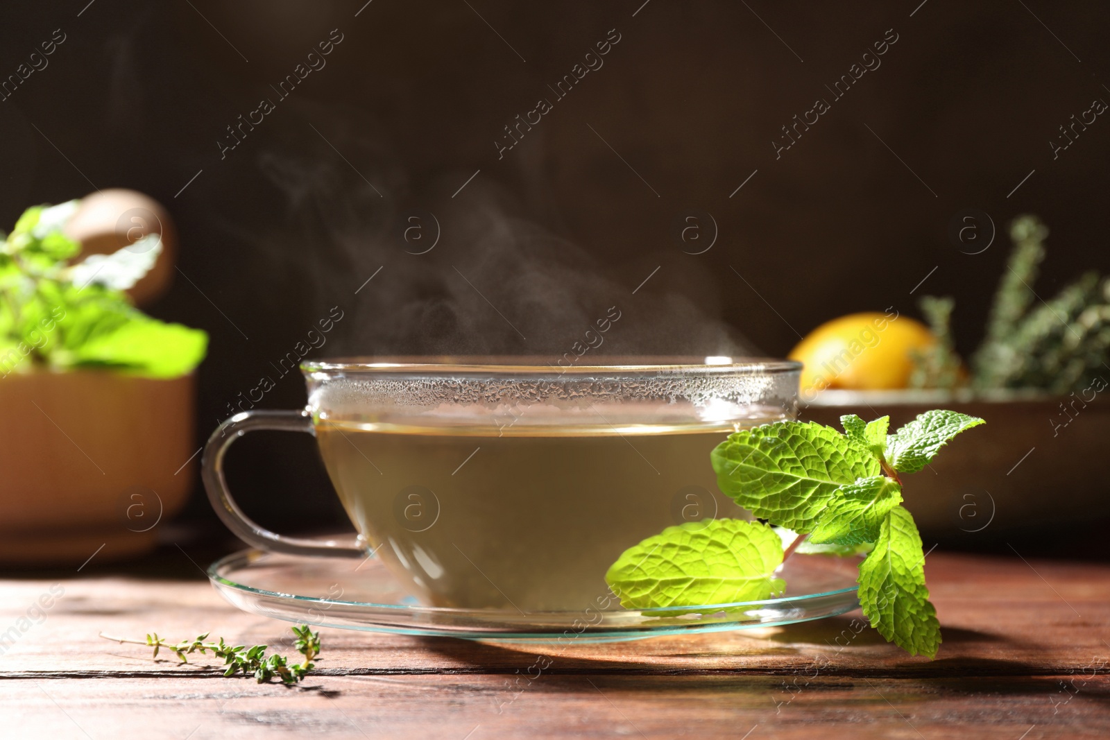 Photo of Cup of aromatic herbal tea and fresh mint on wooden table