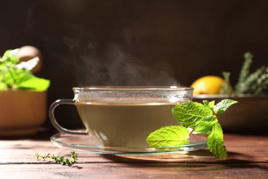 Cup of aromatic herbal tea and fresh mint on wooden table