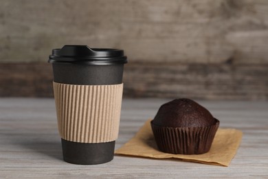 Photo of Paper cup with black lid and muffin on wooden table. Coffee to go