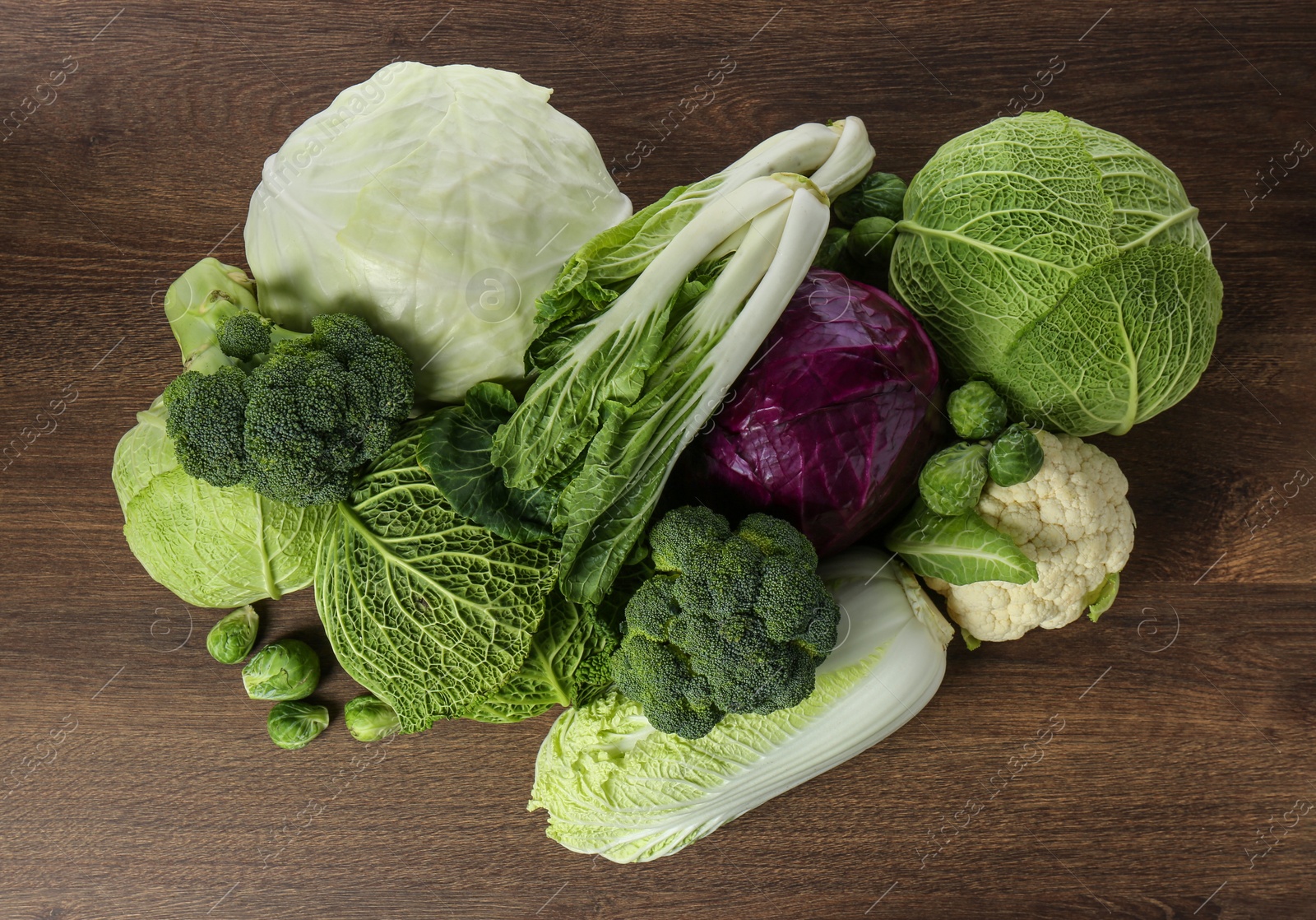 Photo of Many different fresh ripe cabbages on wooden table, top view