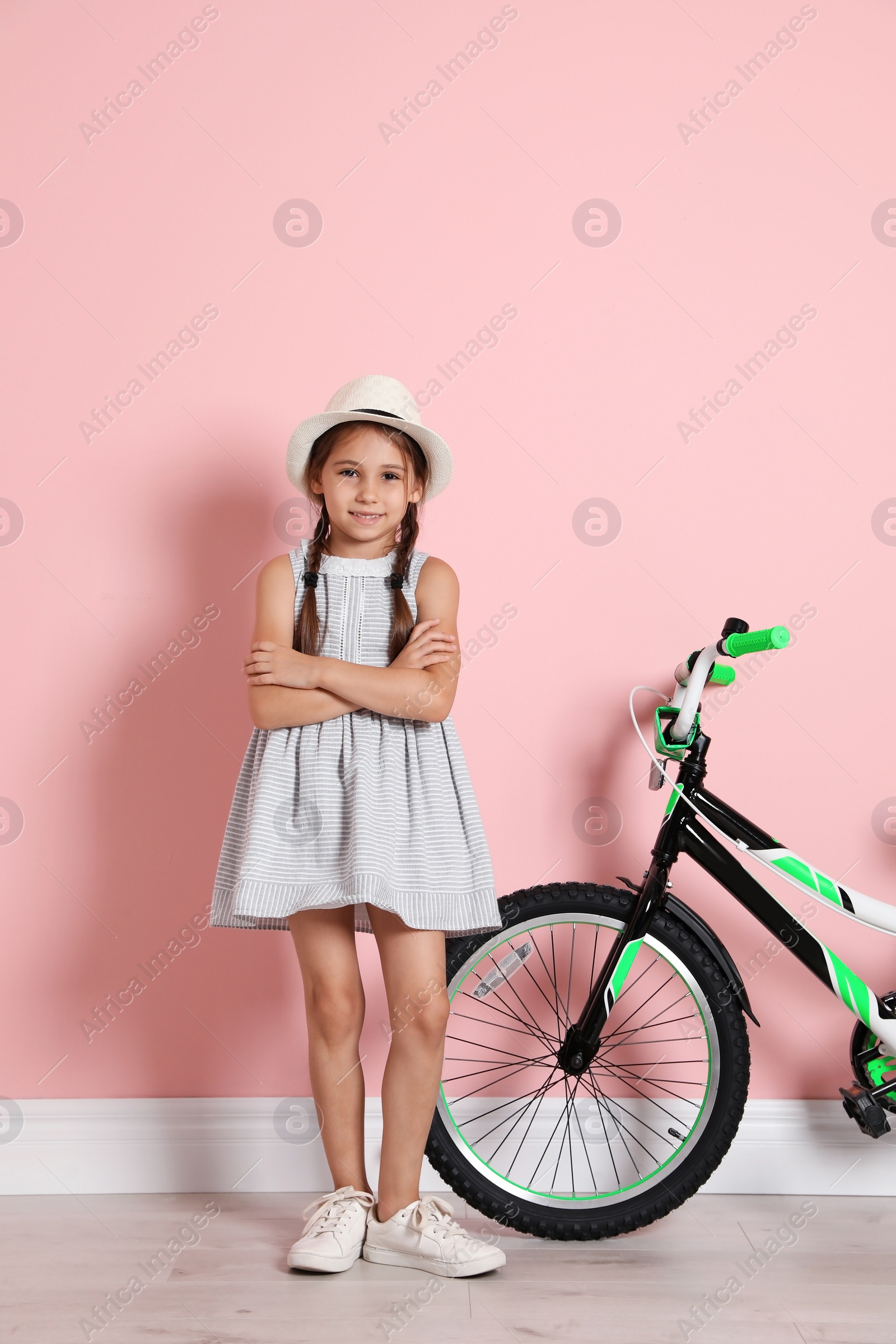 Photo of Portrait of cute little girl with bicycle near color wall