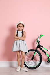 Photo of Portrait of cute little girl with bicycle near color wall