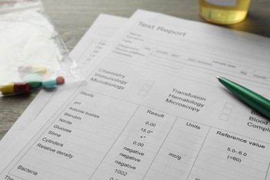 Photo of Drug test result form, pills and pen on table, closeup