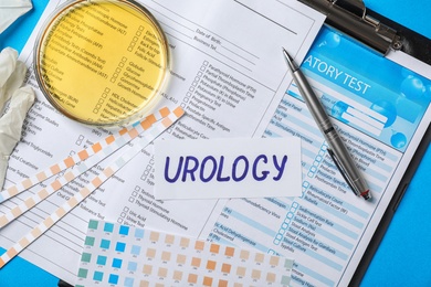 Photo of Flat lay composition with word "Urology" and test forms on color background