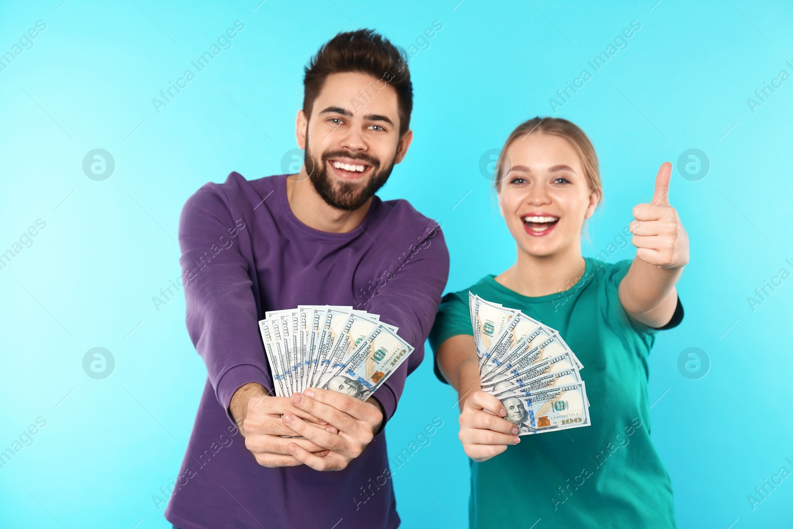 Photo of Happy young couple with money on color background