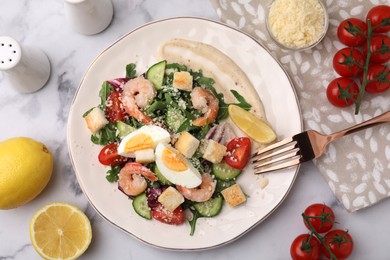 Photo of Delicious Caesar salad with shrimps and ingredients on white marble table, flat lay