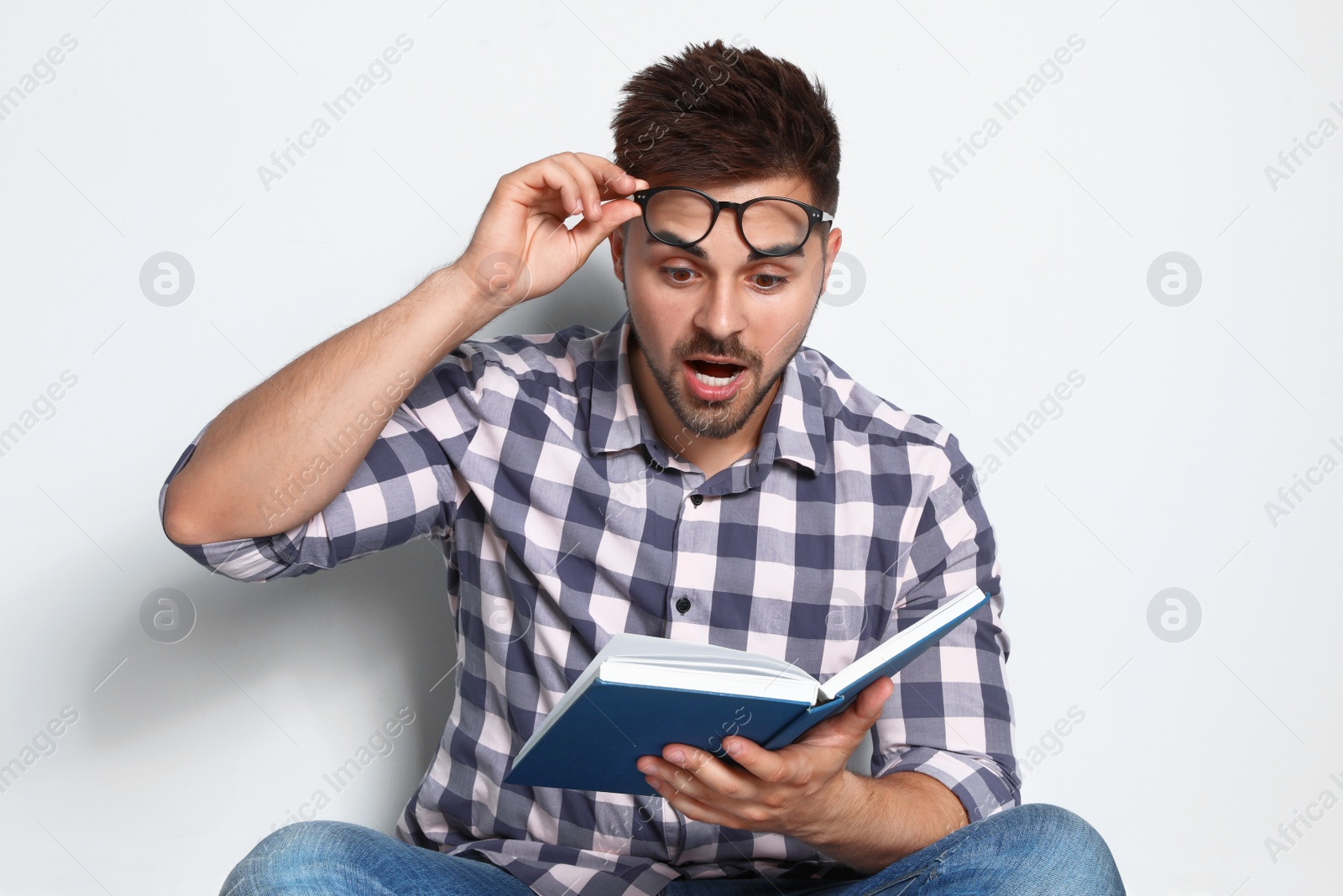 Photo of Handsome young man reading book on light background