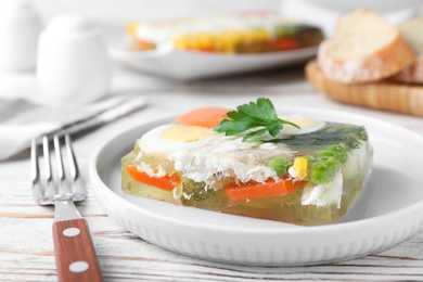 Photo of Delicious fish aspic served on white wooden table, closeup