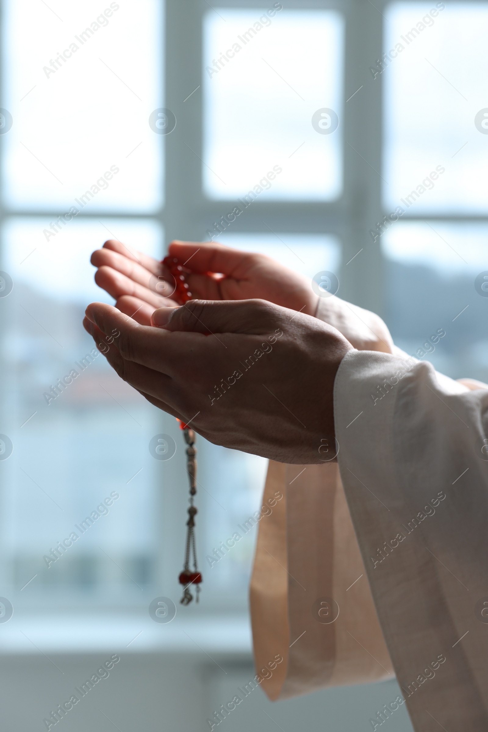 Photo of Muslim woman with misbaha praying indoors, closeup