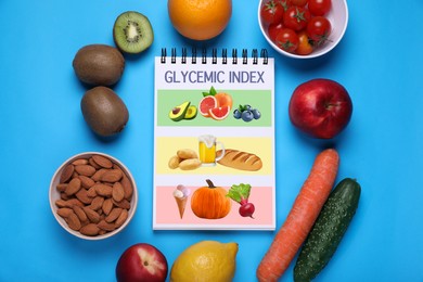 Glycemic index. Information about grouping of products under their GI in notebook, almonds, fruits and vegetables on light blue background, flat lay