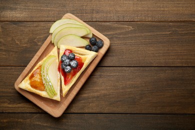 Fresh tasty puff pastry with jam, blueberries and pear on wooden table, top view. Space for text