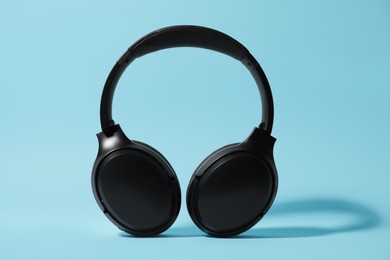 Photo of Modern wireless headphones on light blue background