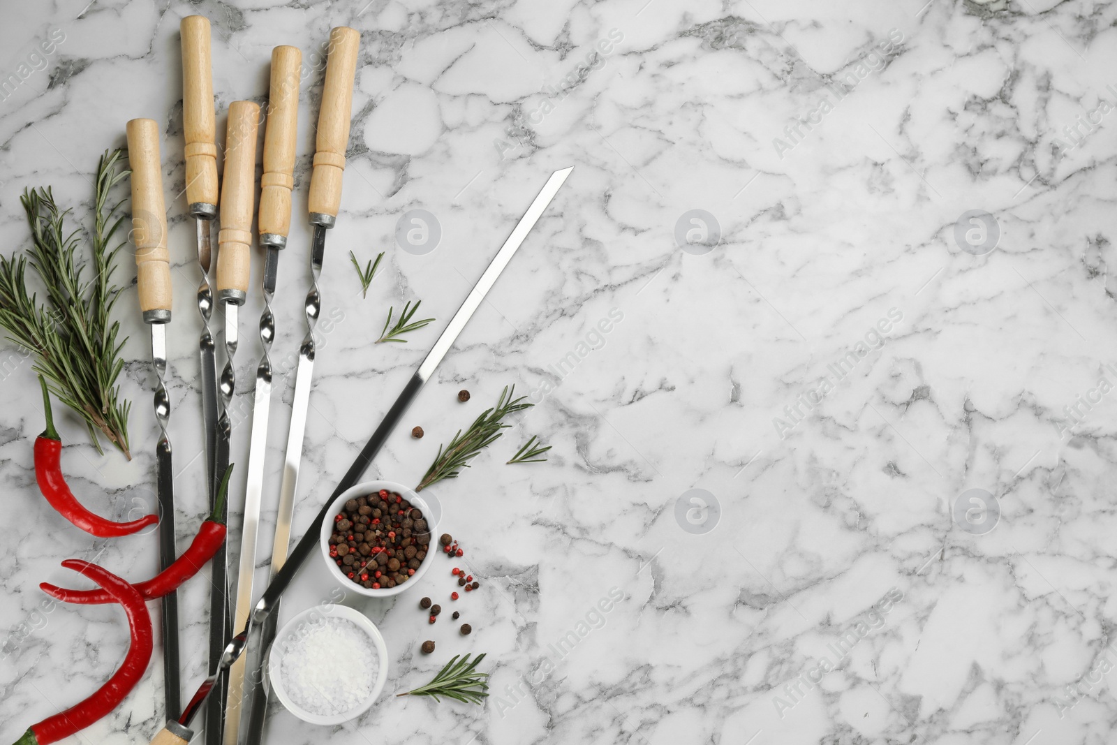 Photo of Flat lay composition with metal skewers on white marble table. Space for text