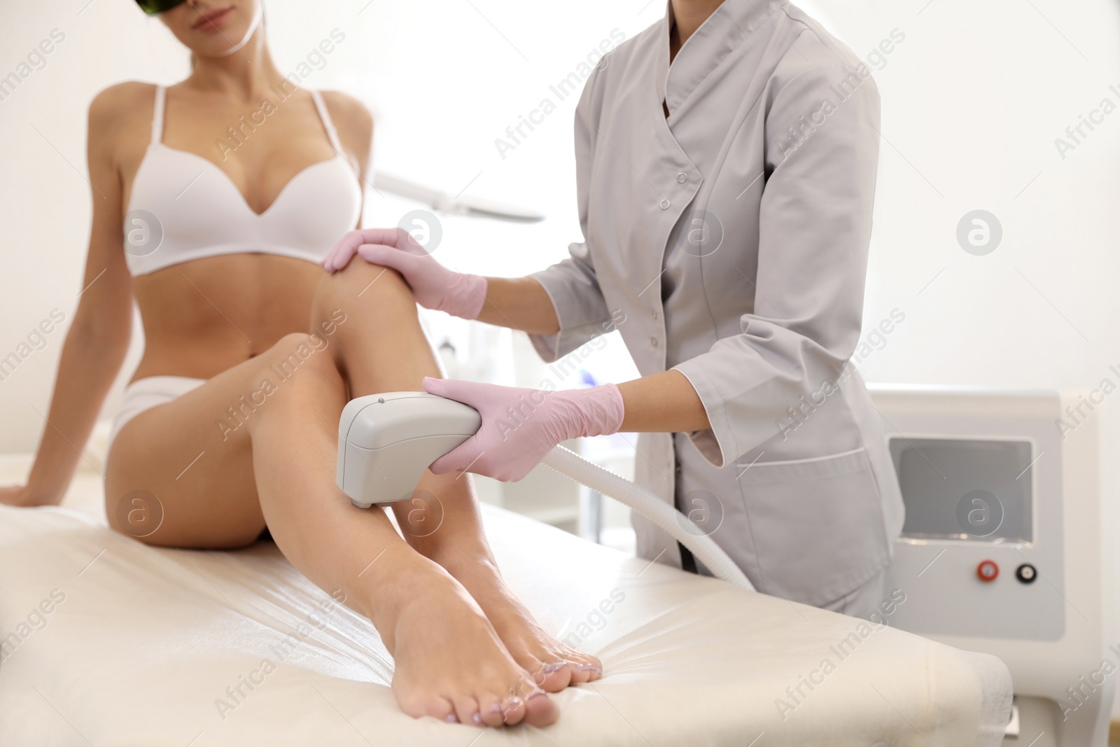 Photo of Young woman undergoing laser epilation procedure in beauty salon, closeup