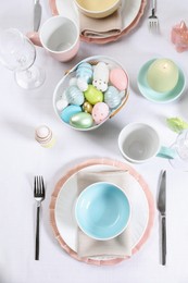 Photo of Festive table setting with painted eggs, flat lay. Easter celebration