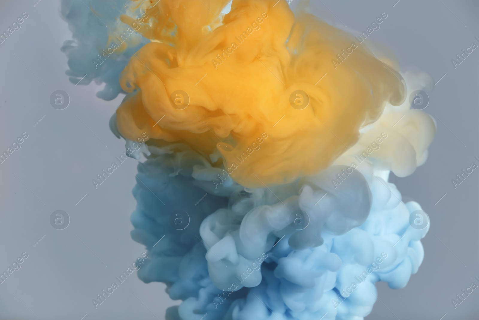 Photo of Splash of yellow and light blue inks on grey background