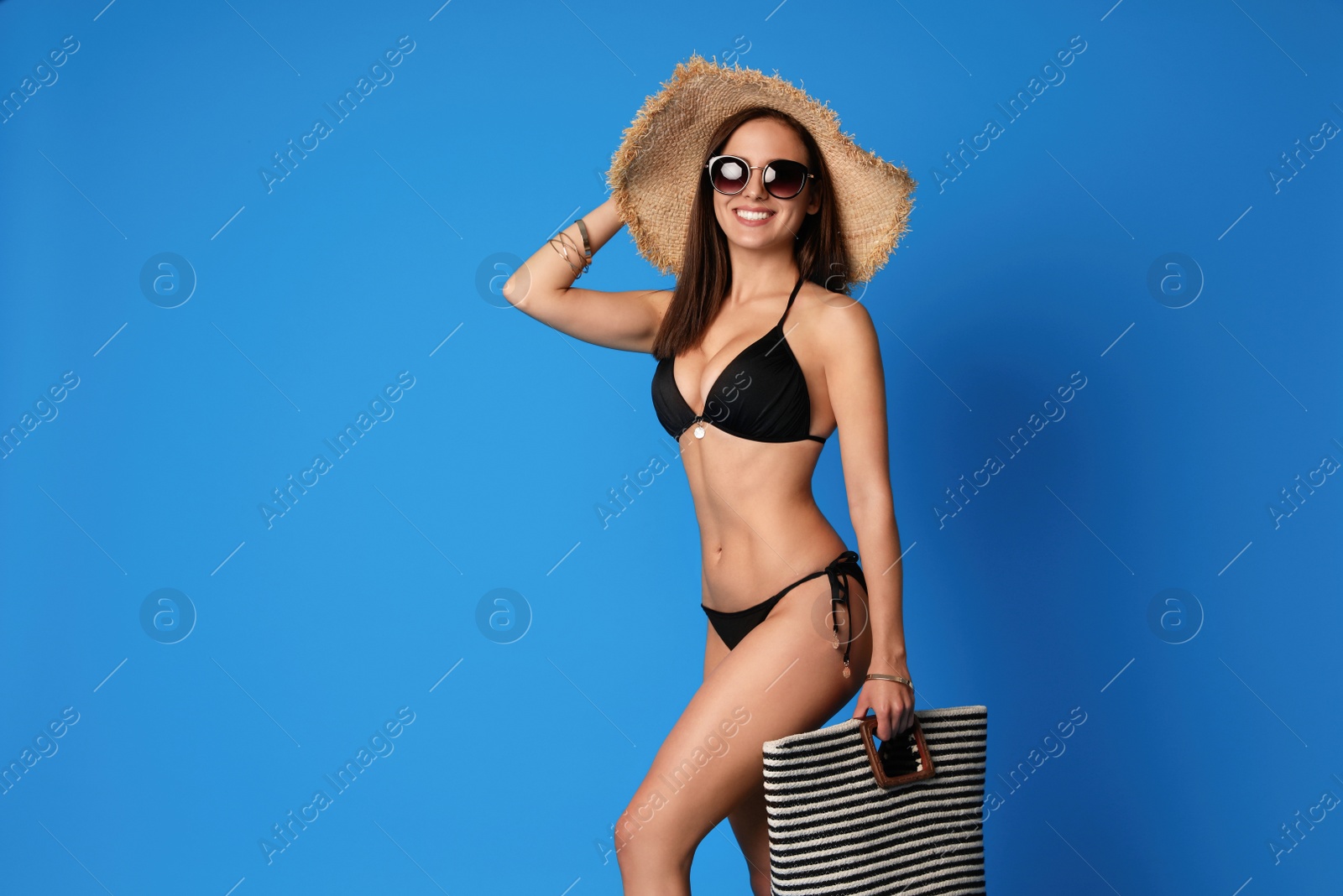 Photo of Pretty sexy woman with slim body in stylish  black bikini on blue background, space for text