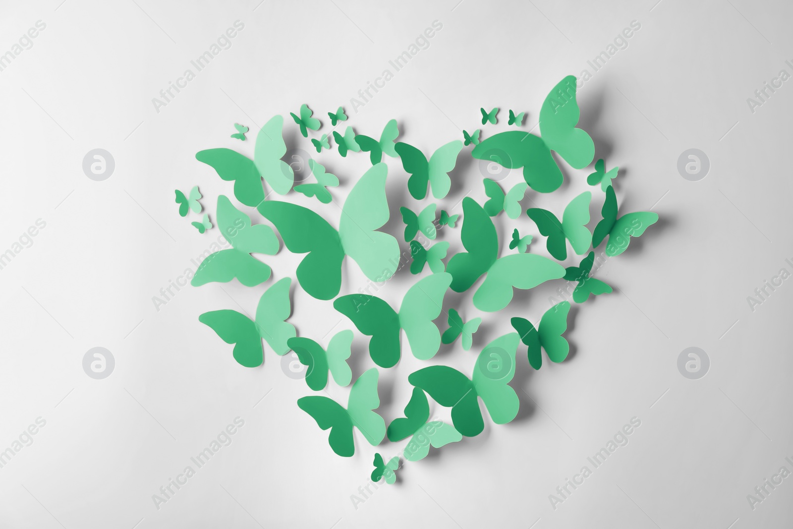 Image of Heart made of green paper butterflies on white wall