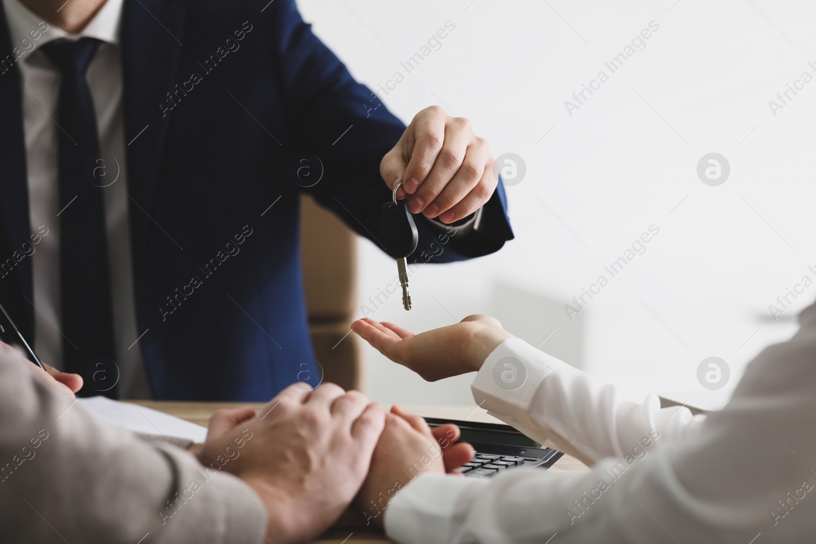 Photo of Salesman giving key to customers in office, closeup. Buying new car
