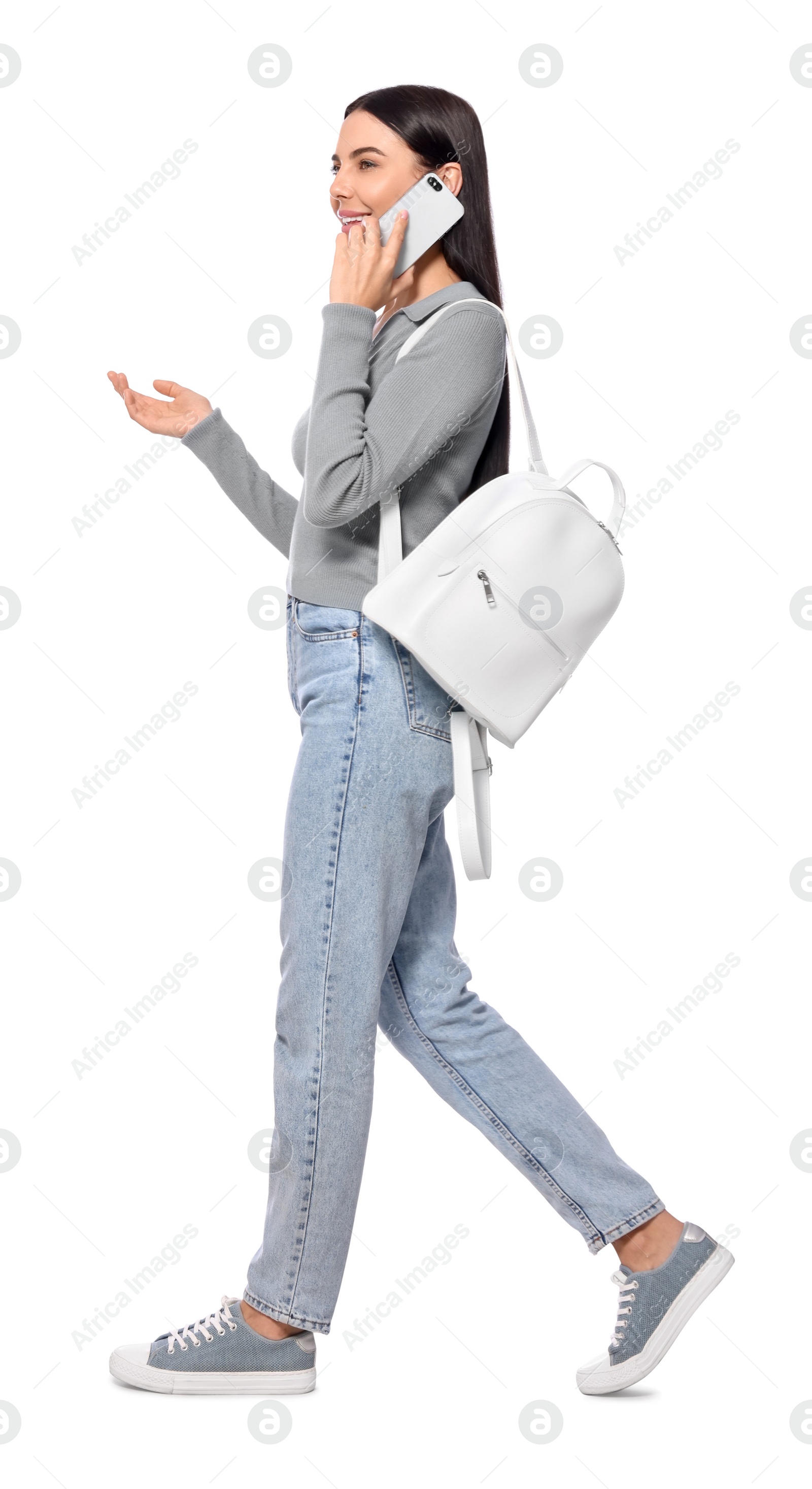 Photo of Young woman talking on smartphone while walking against white background