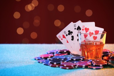 Photo of Alcohol drink, playing cards and casino chips on table against blurred lights. Four of a kind poker combination