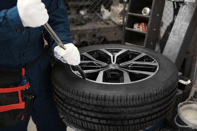 Photo of Technician working with car wheel at automobile repair shop, closeup