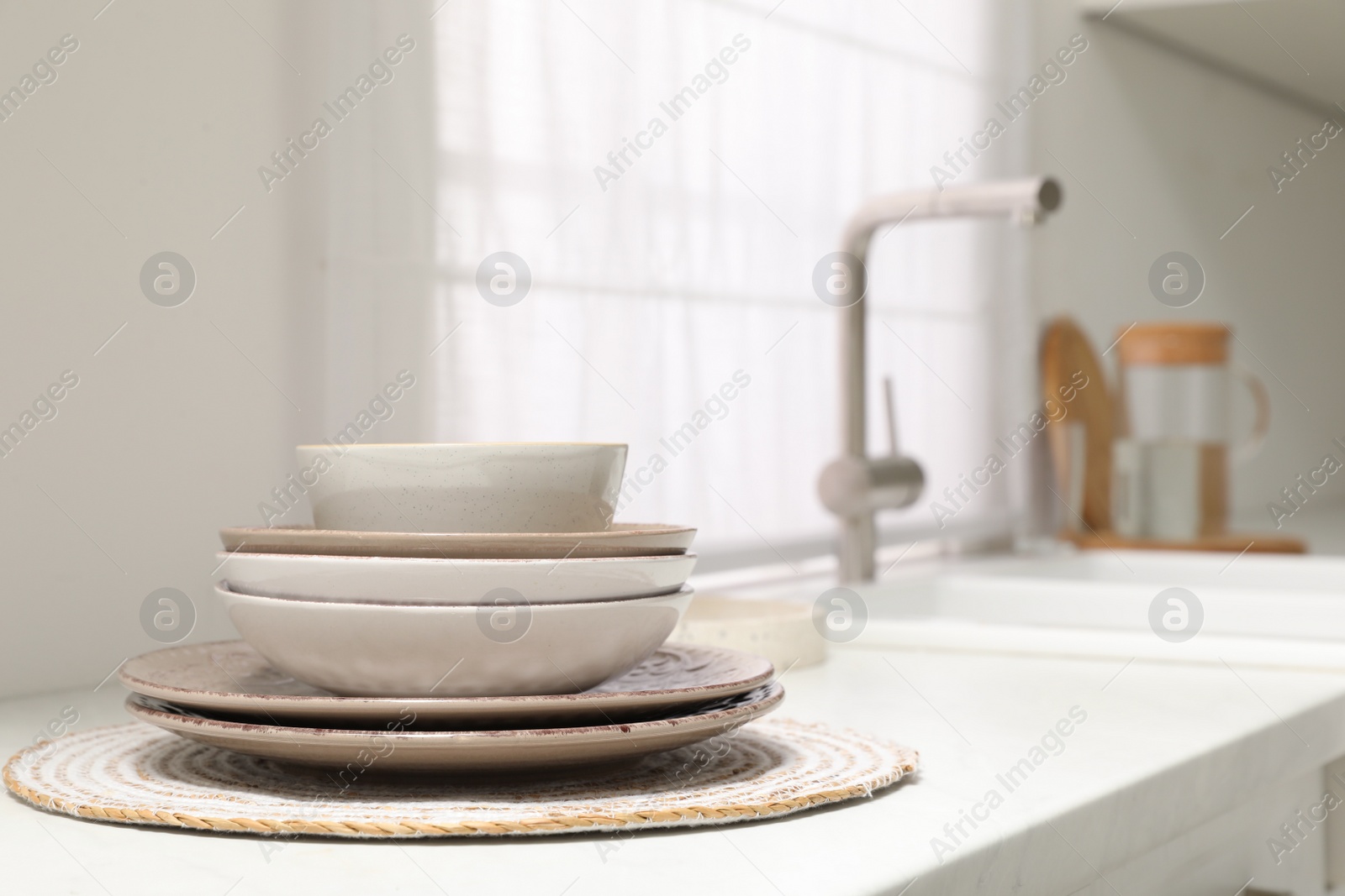 Photo of Stack if clean dishes on countertop near sink in kitchen