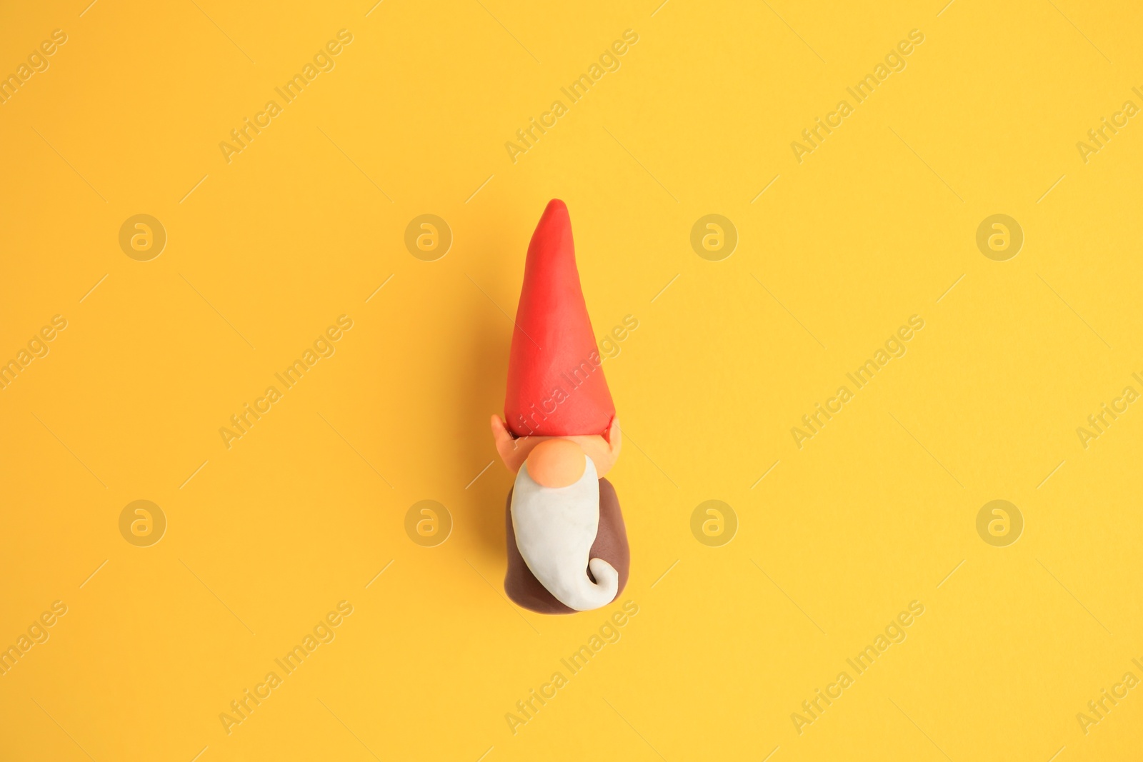 Photo of Dwarf made from plasticine on yellow background, top view. Children's handmade ideas