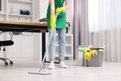 Photo of Cleaning service worker washing floor with mop, closeup. Bucket with supplies in office