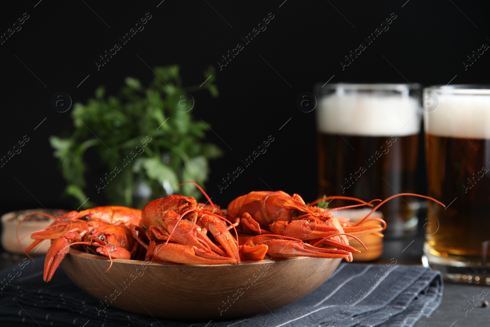 Photo of Delicious red boiled crayfishes on table against black background