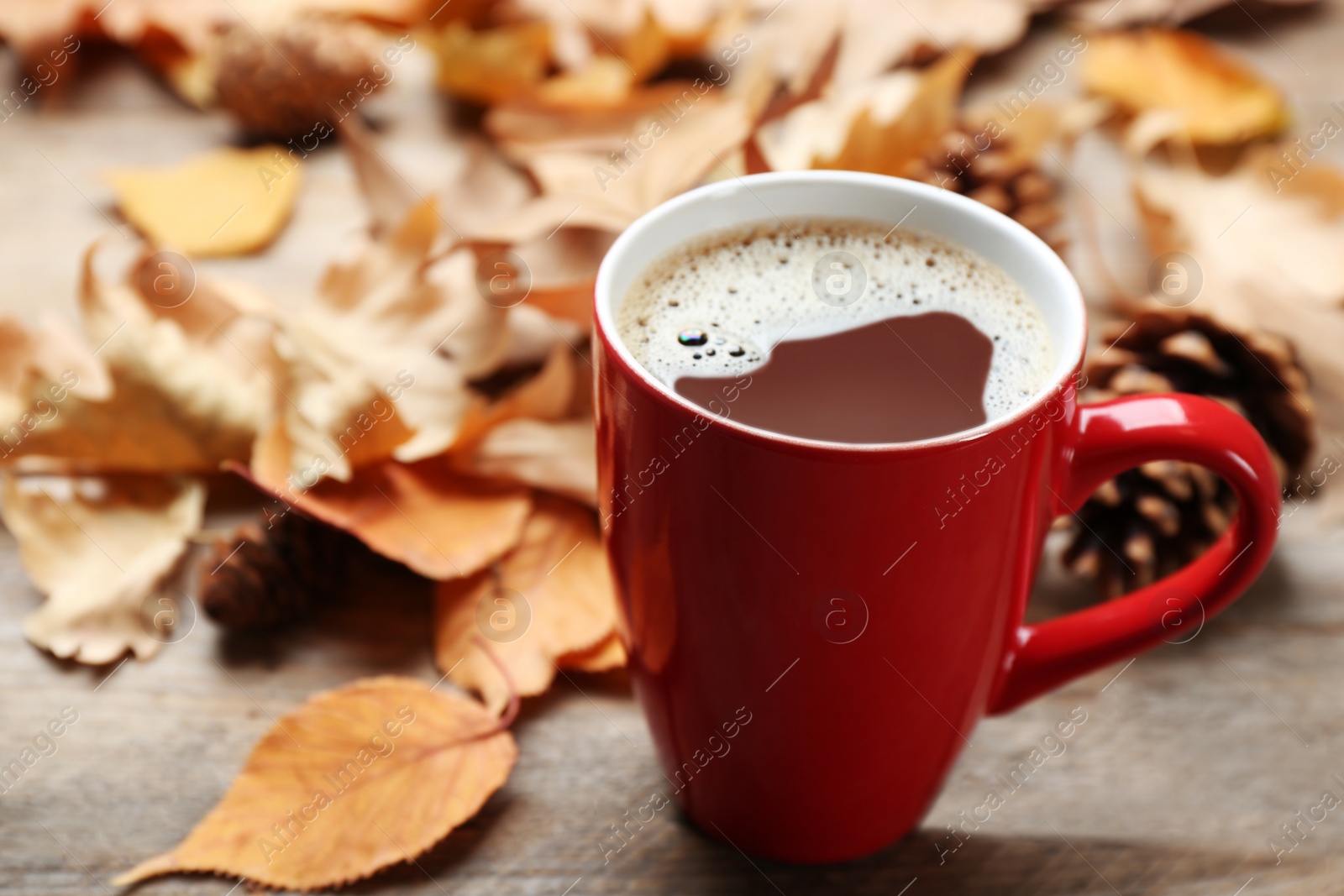 Photo of Cup of hot drink and leaves on wooden table. Cozy autumn atmosphere