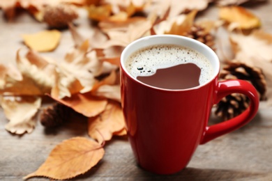 Photo of Cup of hot drink and leaves on wooden table. Cozy autumn atmosphere
