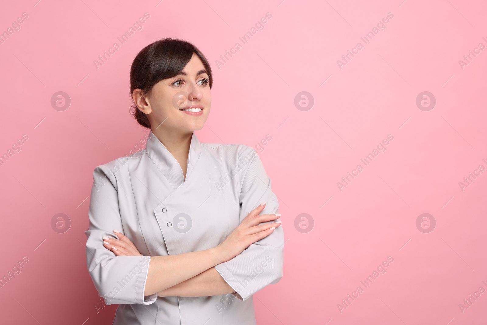 Photo of Cosmetologist in medical uniform on pink background, space for text