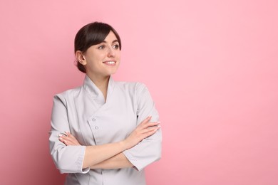 Cosmetologist in medical uniform on pink background, space for text