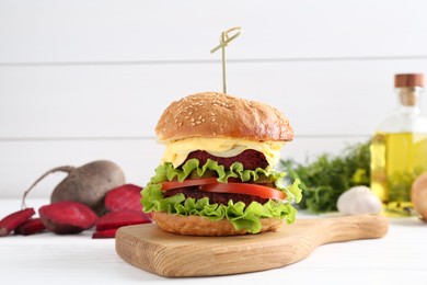 Photo of Delicious vegetarian burger and ingredients on white wooden table