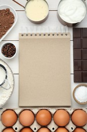 Photo of Blank recipe book surrounded by different ingredients on white wooden table, flat lay. Space for text