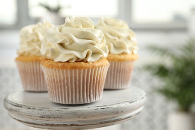 Photo of Tasty cupcakes with vanilla cream on stand, closeup