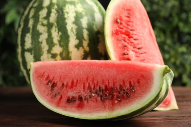 Photo of Whole and cut ripe watermelons on wooden table