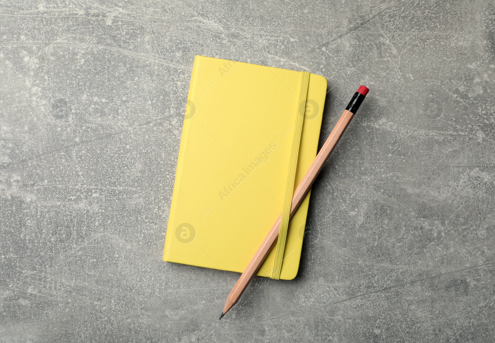 Photo of Yellow planner and pencil on grey table, top view