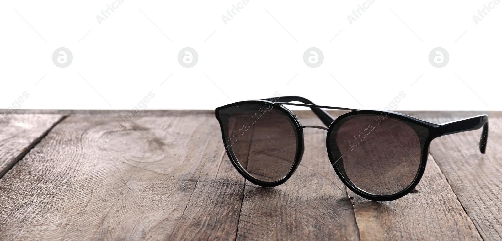 Photo of Stylish sunglasses on wooden table against white background. Space for text