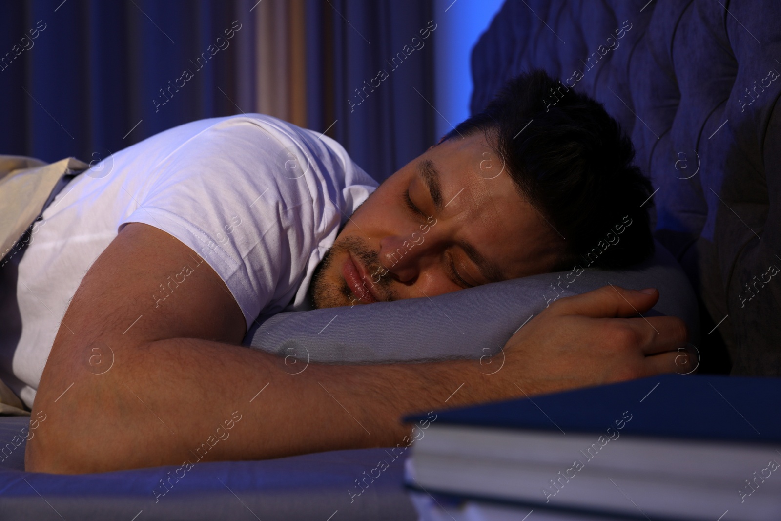 Photo of Handsome man sleeping on pillow in dark room at night. Bedtime