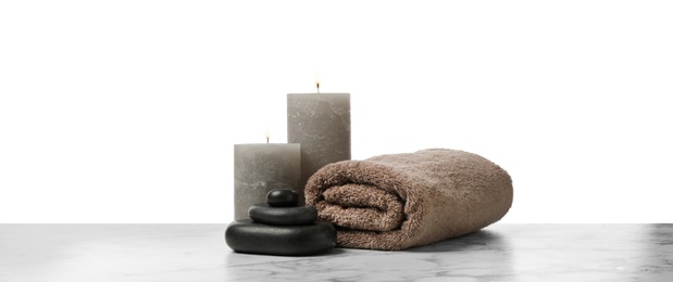 Photo of Spa stones, towel and candles on marble table against white background