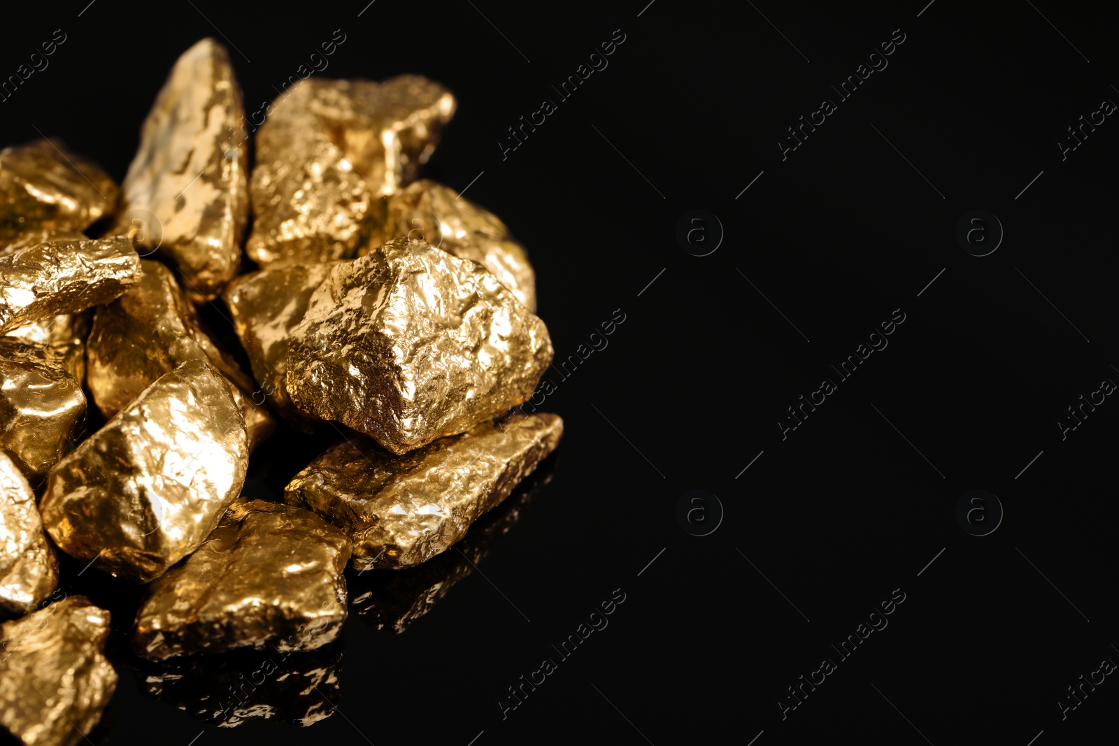 Photo of Pile of shiny gold nuggets on black background, closeup. Space for text