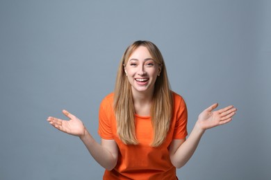 Beautiful young woman laughing on grey background. Funny joke