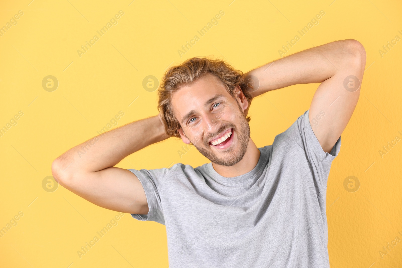 Photo of Handsome young man laughing on color background