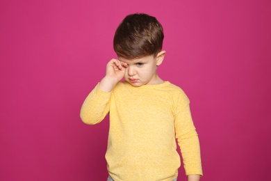 Photo of Little boy rubbing eye on color background. Annoying itch