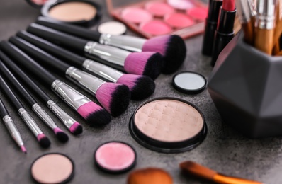 Makeup products and brushes on grey background